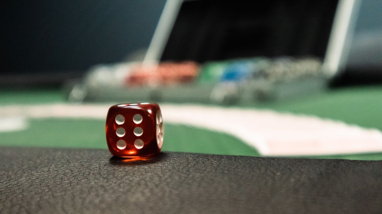 services-02 A close-up of a red dice on a casino table, evoking a sense of gambling excitement.