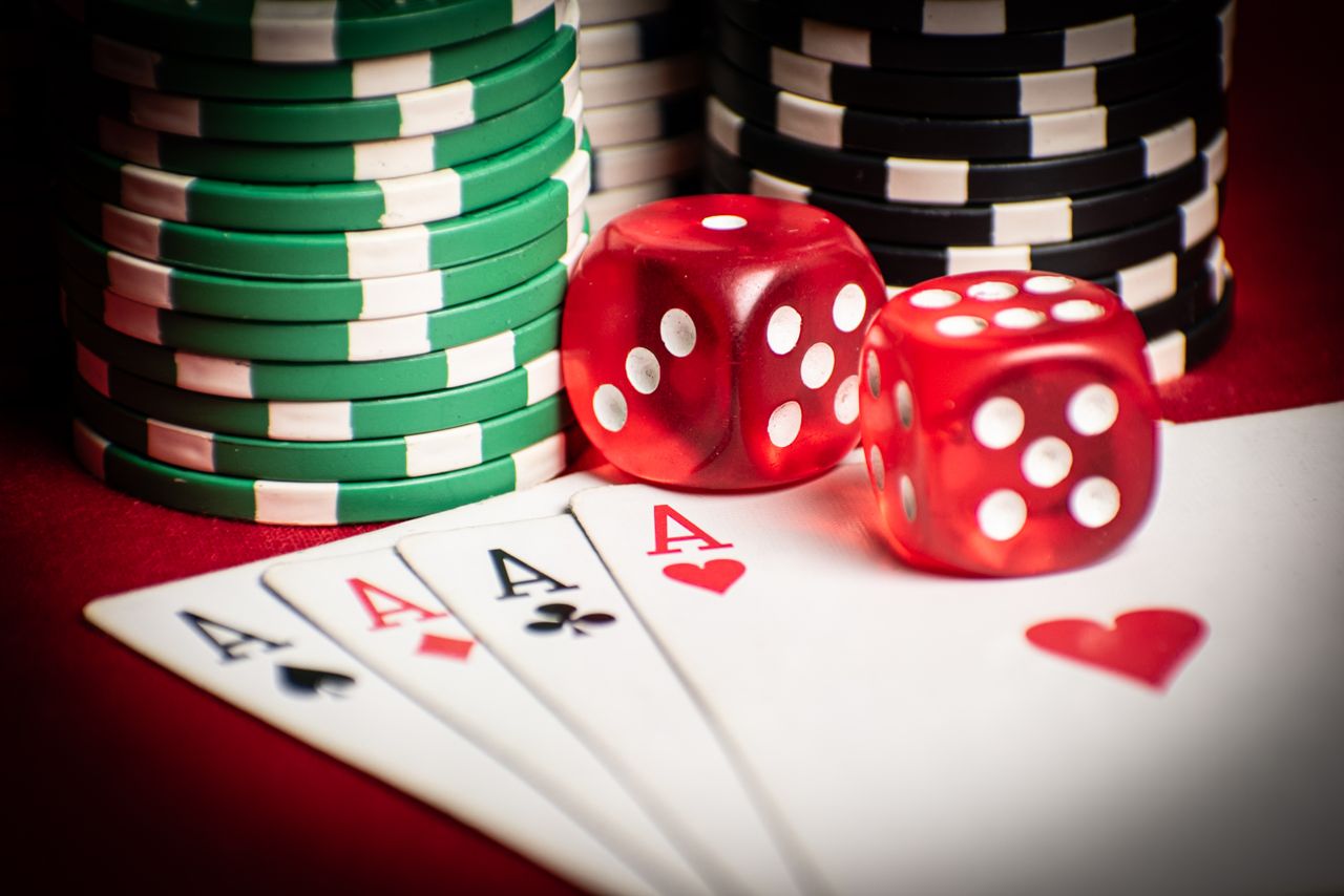 gallery-4 Close-up of poker hand with dice and chips, symbolizing casino gaming.
