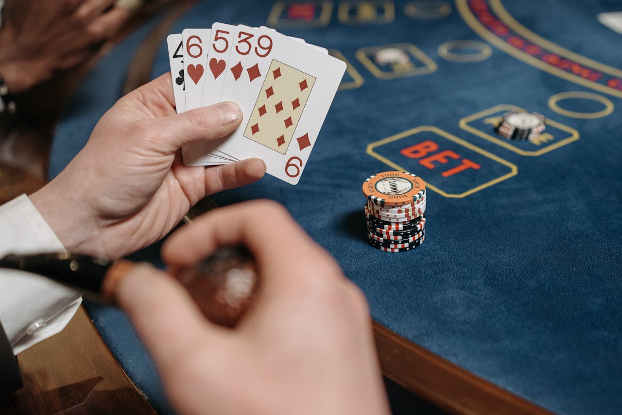 contact-img A gambler holding cards at a casino table filled with gaming chips.