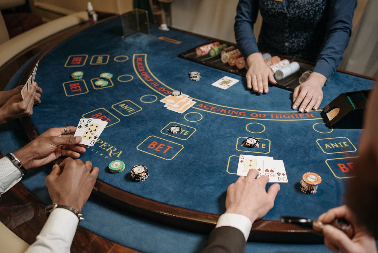 gallery-1 People playing a lively card game at a casino table with chips and a dealer.