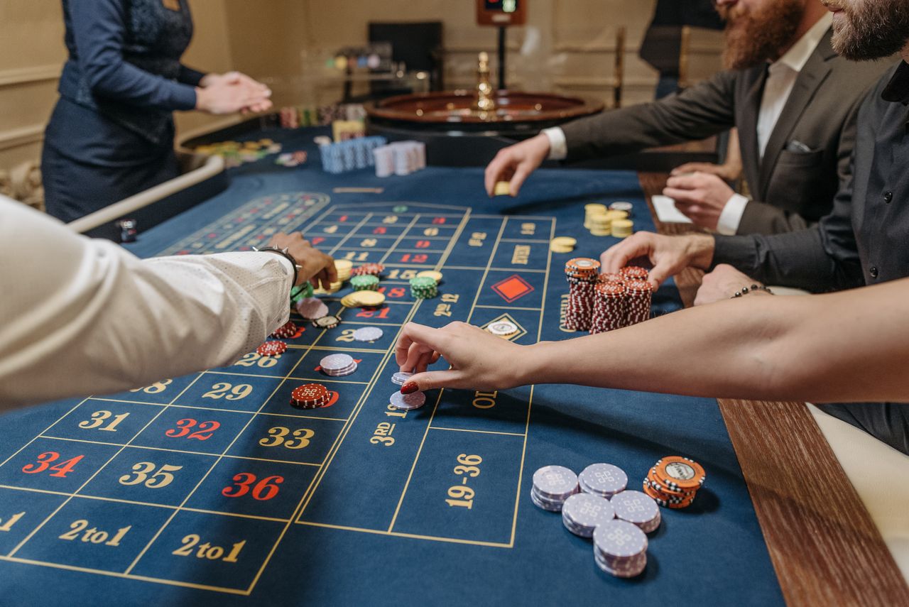 gallery-3 A lively casino scene with players placing bets and handling gaming chips on a roulette table.